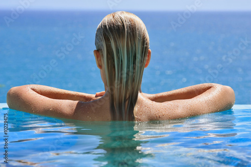 Jeune femme blonde dans une piscine avec vue sur mer