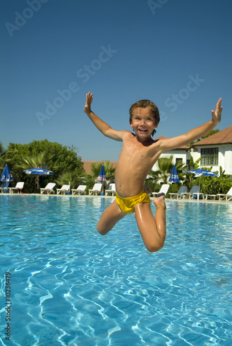 boy jumping into the pool smiling