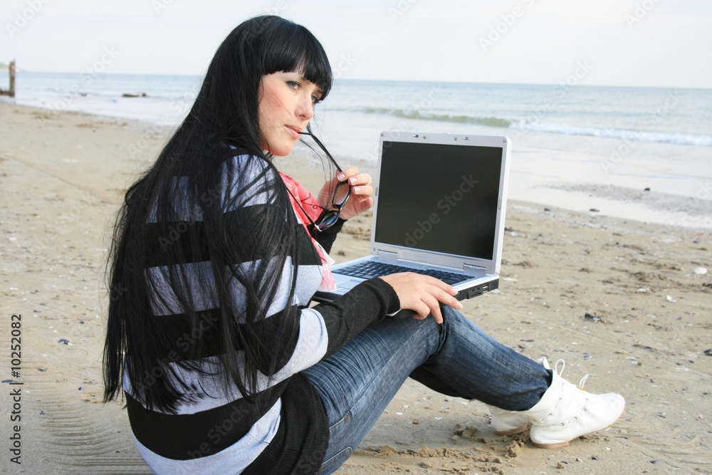 Young woman working with computer at the beach