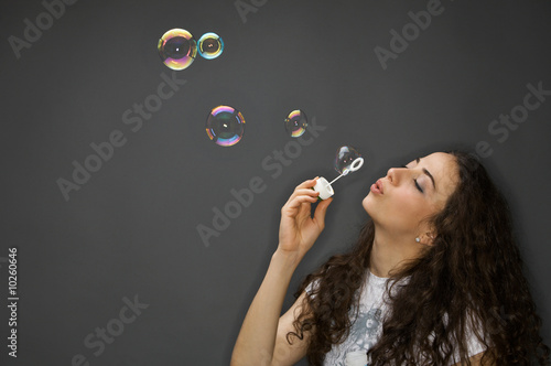 young pretty woman with soap bubbles over grey