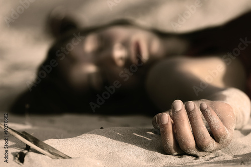 woman playing dead, lying in the sand