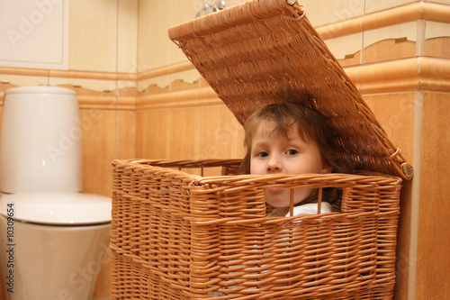Girl in basket for linen in bathroom