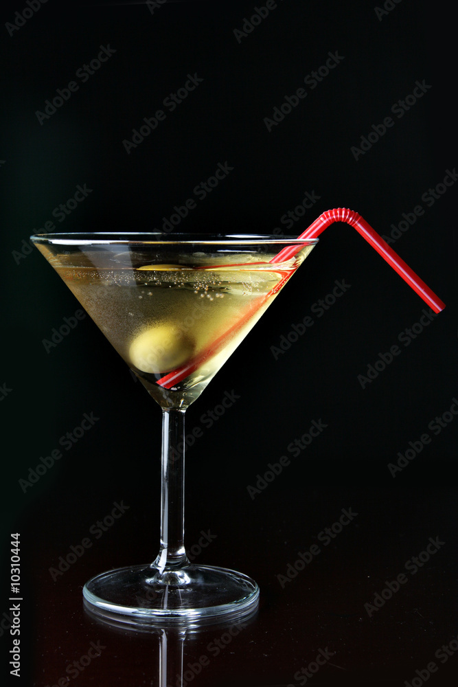 Cocktail glass with ice and olive close-up over black background