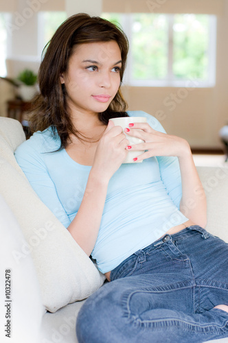 An attractive young woman drinking coffee at home