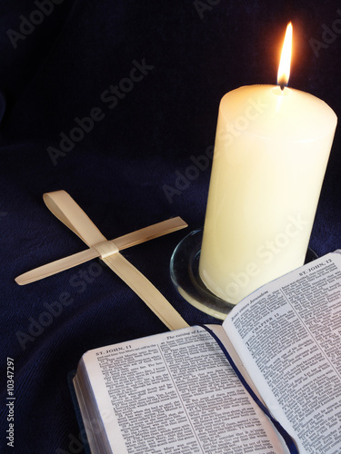Lit cadle with bible open at Palm Sunday story, and palm crosses