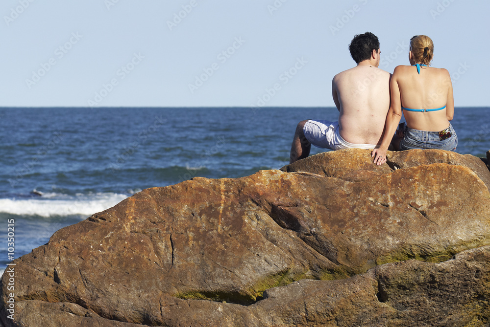 Paar sitzt auf einem Felsen am Meer Paar sitzt auf einem Felsen am Meer