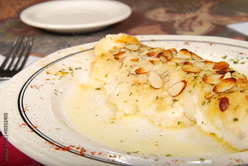 Fish with almonds on a white plate on a table