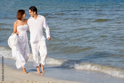 happy wedding couple walking along seashore