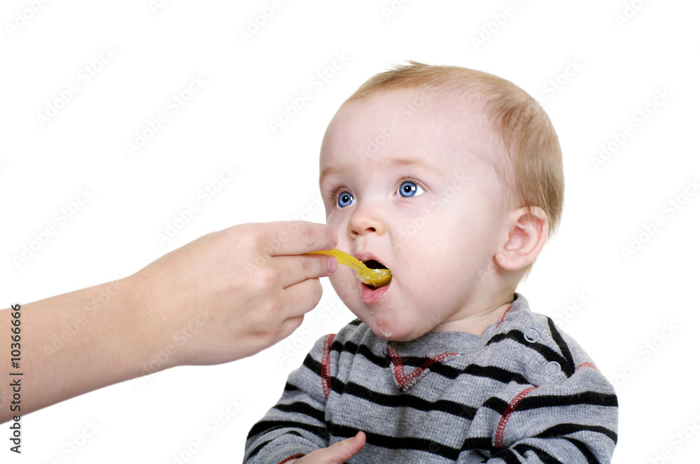 Cute baby being feed rice cereal with a yellow spoon Cute baby being feed rice cereal with a yellow spoon