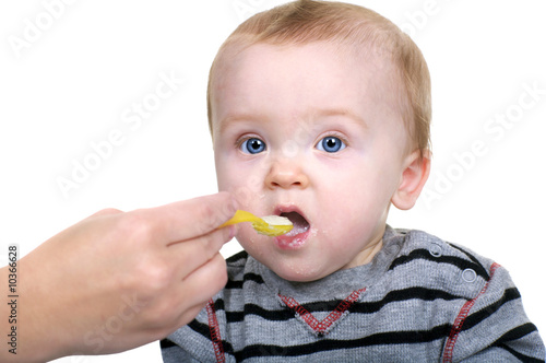 Beautiful baby being feed rice cereal with a yellow spoon