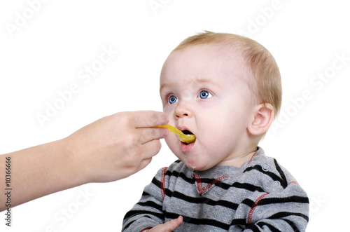Cute baby being feed rice cereal with a yellow spoon