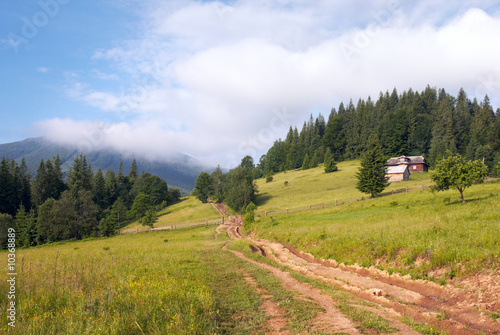 Summer mountain landscape with rural road and house