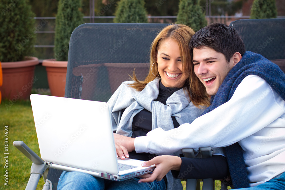 Happy Young couple surfing the internet outside Happy Young couple surfing the internet outside