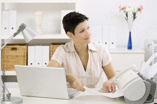 Woman using fax machine at home office. photo