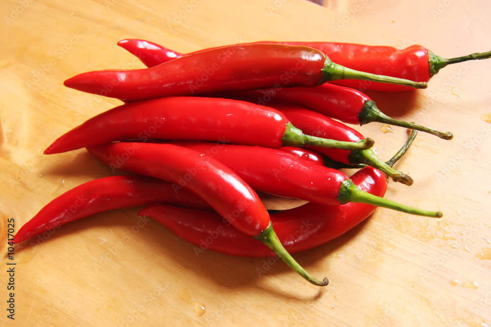 Fresh whole red chillis on chopping board