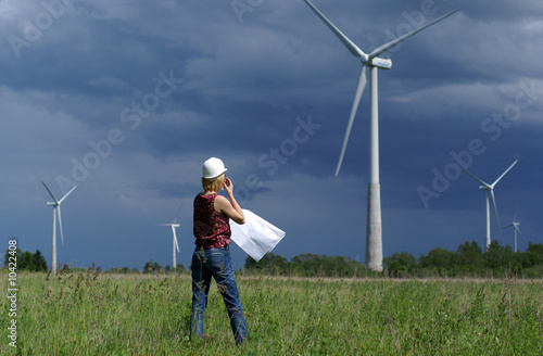 Woman engineer or architect with safety hat and wind turbines
