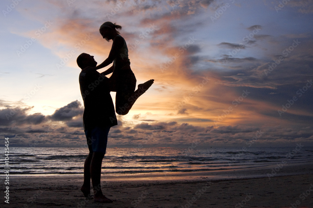 young couple having fun on the beach during sunset