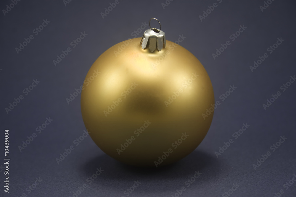 Single gold ornament isolated against blue paper Single gold ornament isolated against blue paper