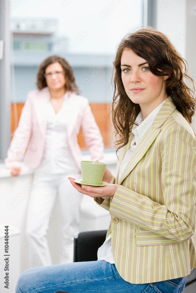 Young businesswomen having break at office drinking coffee. Young businesswomen having break at office drinking coffee.