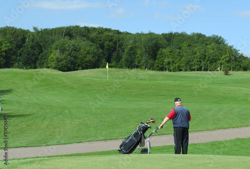 Senior man holding his caddie on a golf course