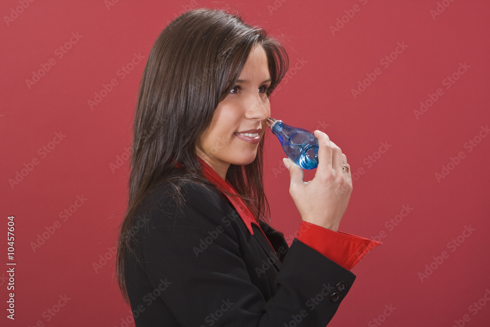 Young brunette woman smelling a perfume bottle Young brunette woman smelling a perfume bottle