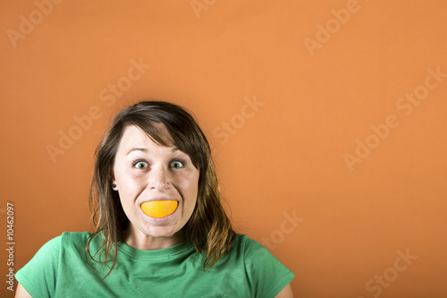 Girl Smiling with Orange in Mouth