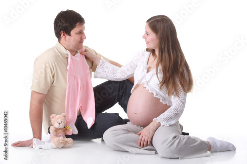 Obraz na płótnie Couple waiting for baby sitting and looking on baby clothes w salonie