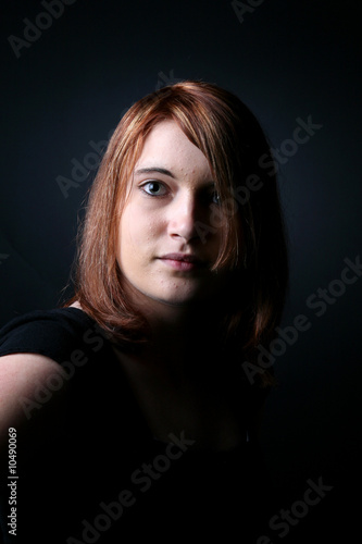 dramatically lit portrait of a red haired teen in black