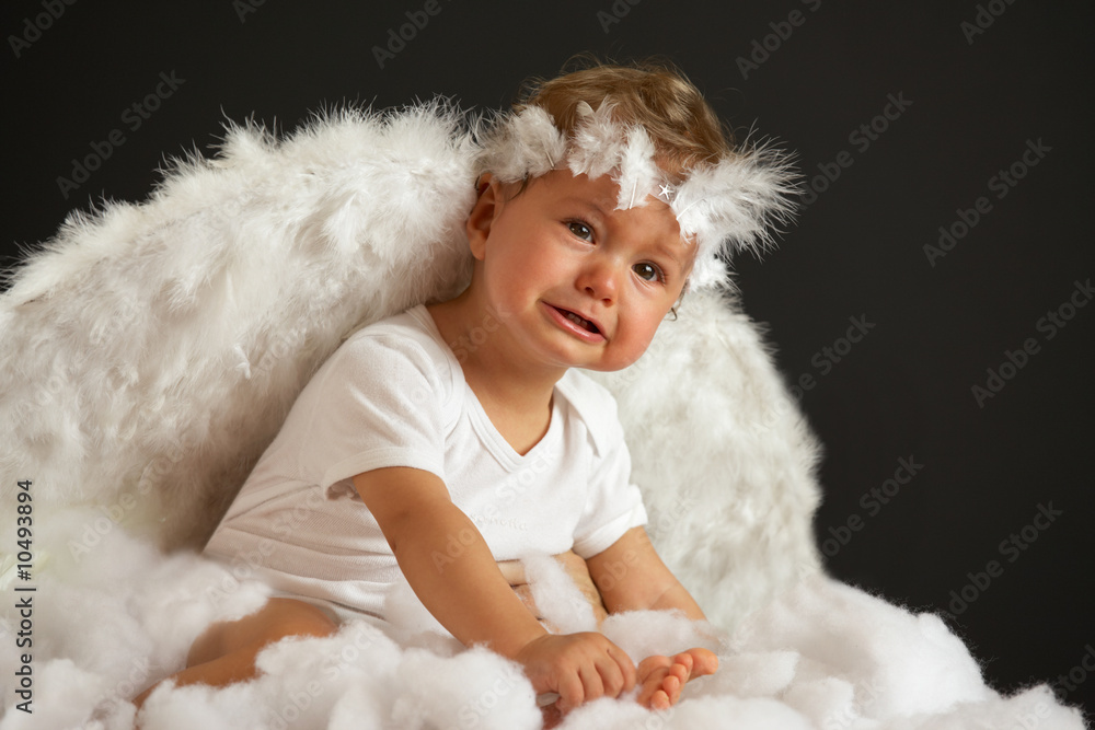 baby girl with angel wings in soft white batting, not amused baby girl with angel wings in soft white batting, not amused