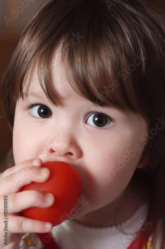 Small girl eating tomato