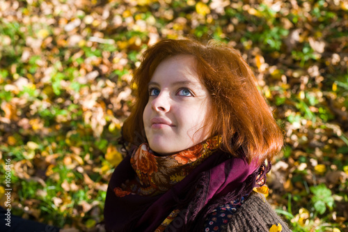 Portrait of the girl with blue eyes against autumn foliage