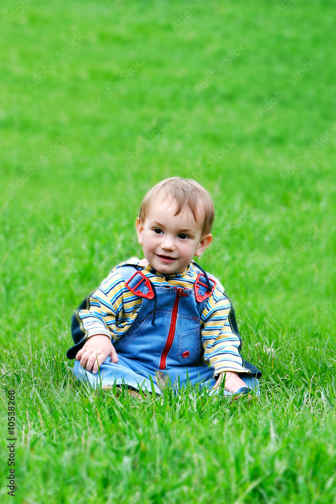 young boy sitting in green grass young boy sitting in green grass