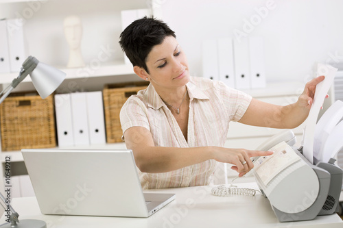Φωτογραφία Woman using fax machine at home office.