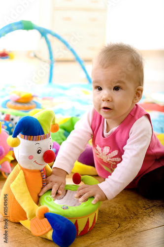 Baby girl (9 months) playing with soft toys at home.
