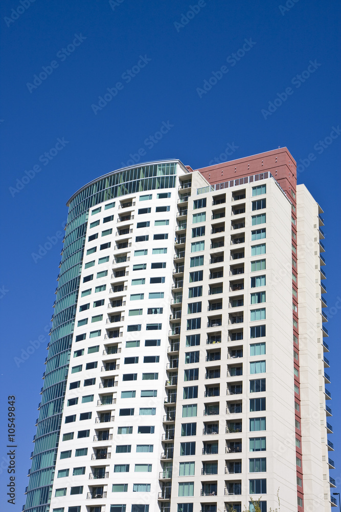 A modern high rise condominium building against a blue sky
