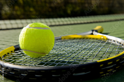 A tennis racket and new tennis ball on a tennis court © Michael Flippo