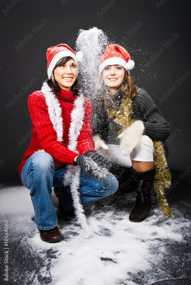 Obraz premium Girls wearing Christmas caps playing with snow.