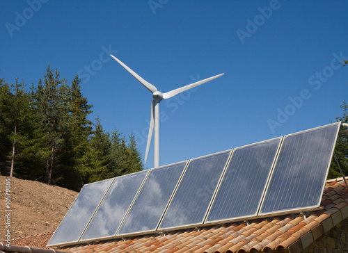 Développement durable : toit couvert de six panneaux solaires et une éolienne blanche photo