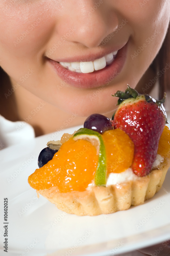 Young woman with low-calorie fruit cake (focus on face) Young woman with low-calorie fruit cake (focus on face)