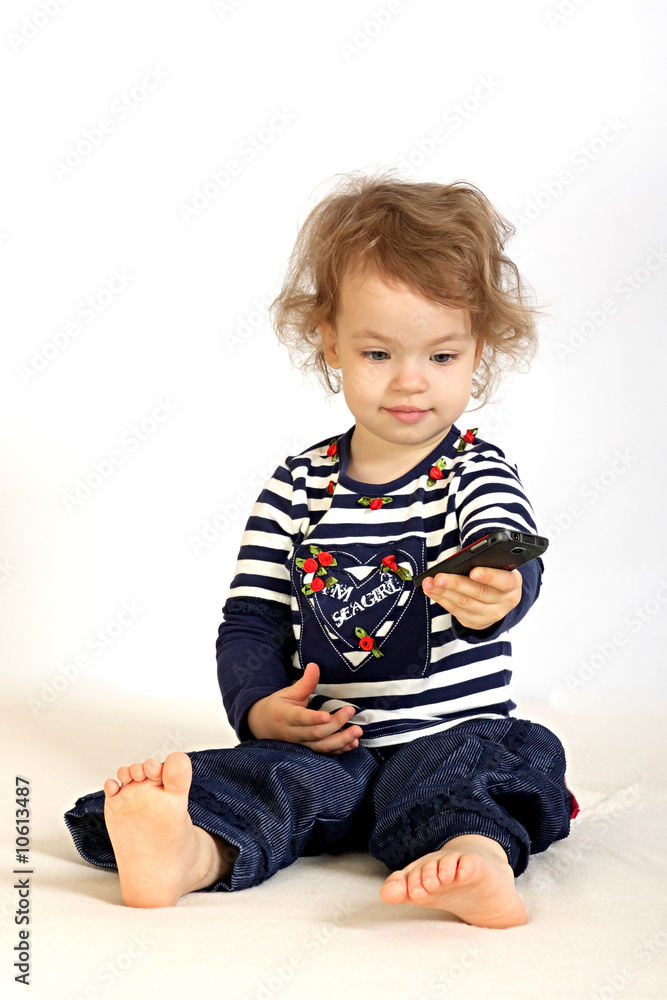 A little girl studies a telephone.