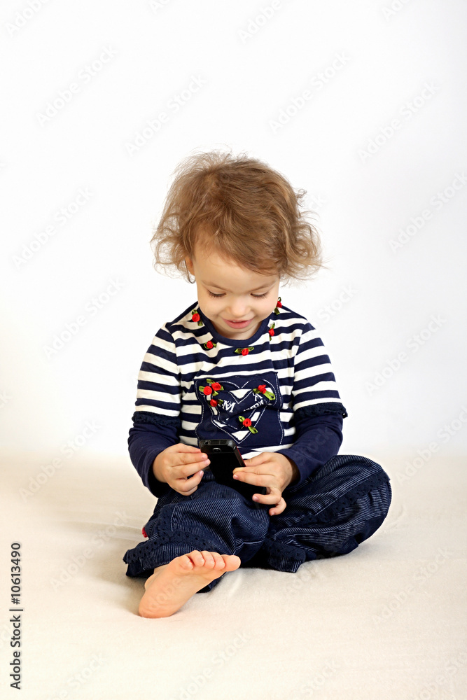 A little girl studies a telephone. A little girl studies a telephone.