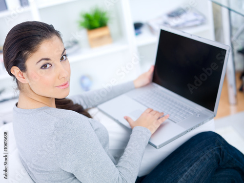 Young woman sitting on couch and working on laptop