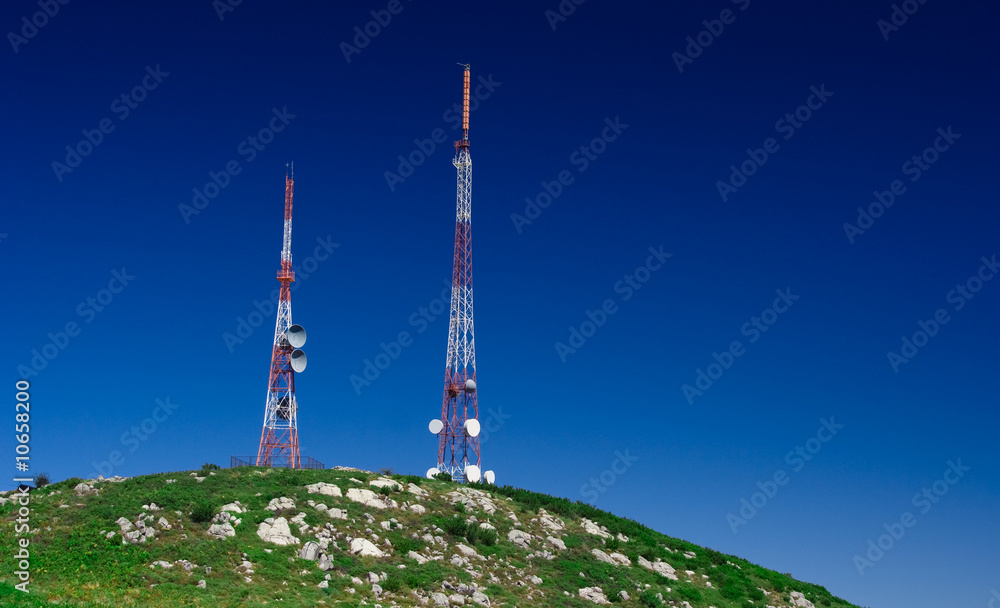 Telecommunication tower on the green field with blue sky