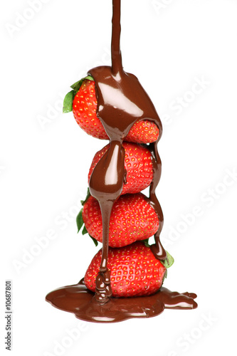 Pouring melted chocolate over four strawberries