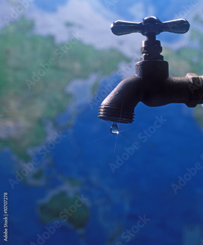 Canvas Print water faucet with one drop of water over a world map