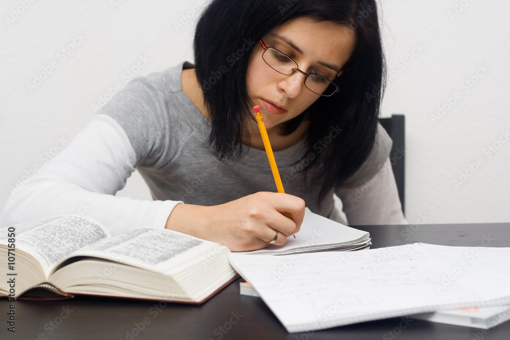 young caucasian woman sitting behind the desk and studying young caucasian woman sitting behind the desk and studying