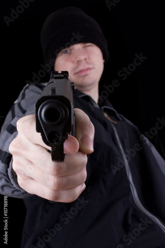 Young man with gun on black background