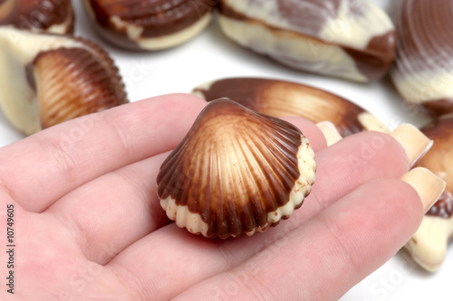 Girl holding chocolate sea shell against white
