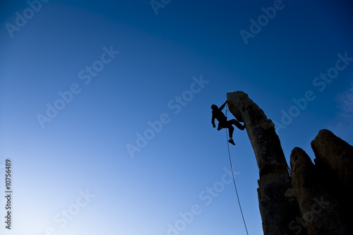 Climber dangling from a pinnacle.