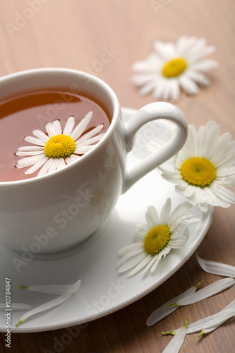 white cup of herbal tea and camomile flowers